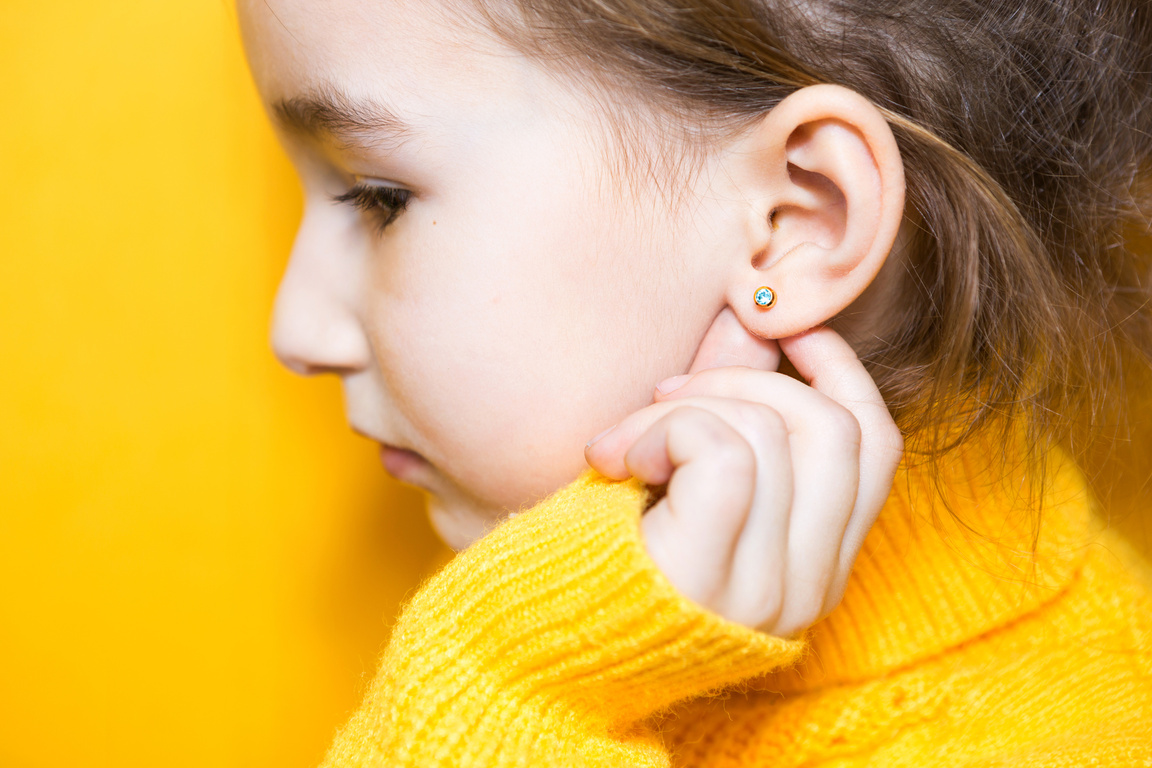 Ear Piercing in a Child - a Girl Shows an Earring in Her Ear Mad
